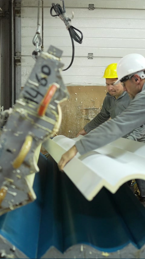 Technicians inspect a newly formed curved decorative moulding section.