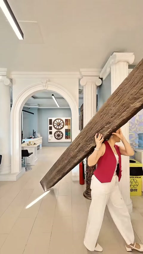 Una collaboratrice passa un lungo pezzo di trave con motivo in legno attraverso l'area della vetrina.