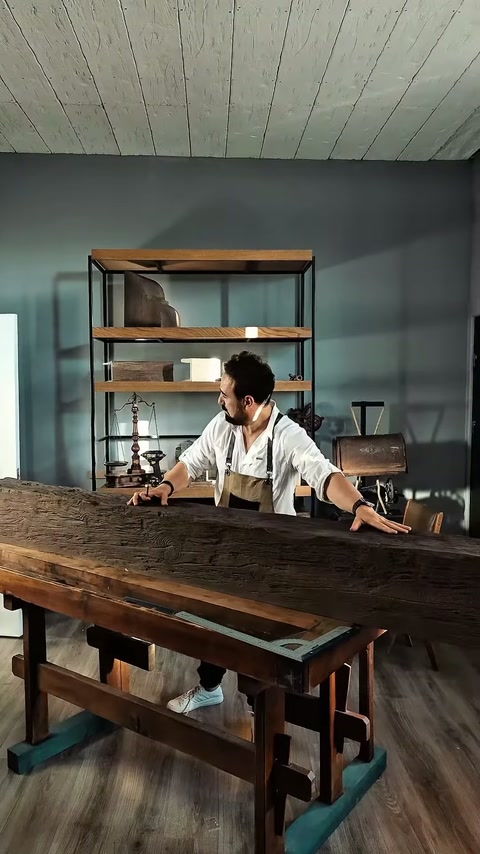 Il maestro controlla manualmente il pezzo di trave sul banco di lavoro.