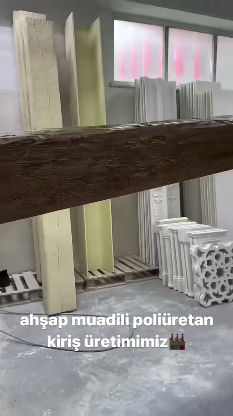 Un operatore tiene in posizione orizzontale la trave decorativa con texture effetto legno