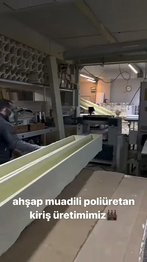 I profili in poliuretano lunghi rimangono paralleli accanto al banco di lavoro della produzione.