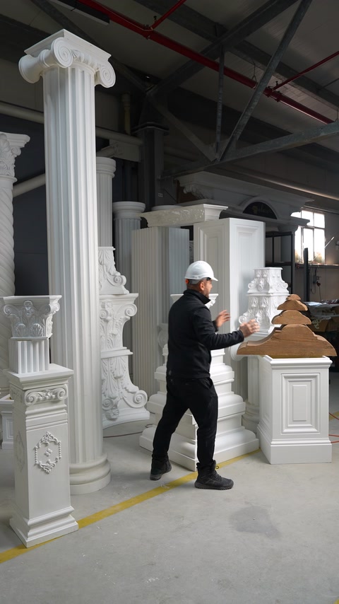 Il presentatore esamina profili effetto legno accanto a elementi architettonici bianchi.