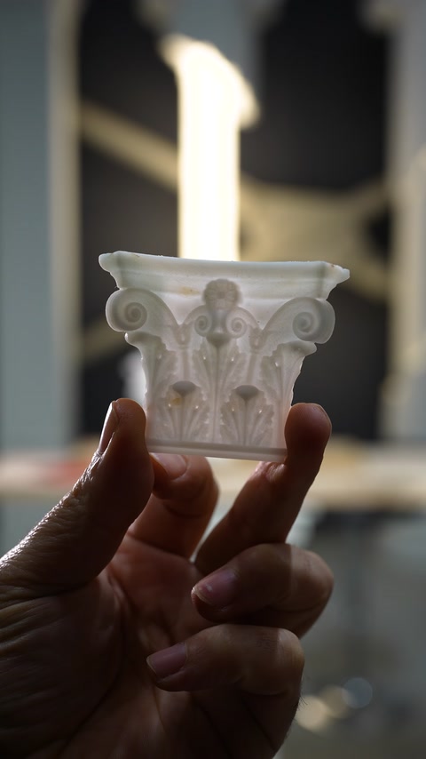 I motivi curvilinei di un capitello in miniatura sono mostrati da vicino