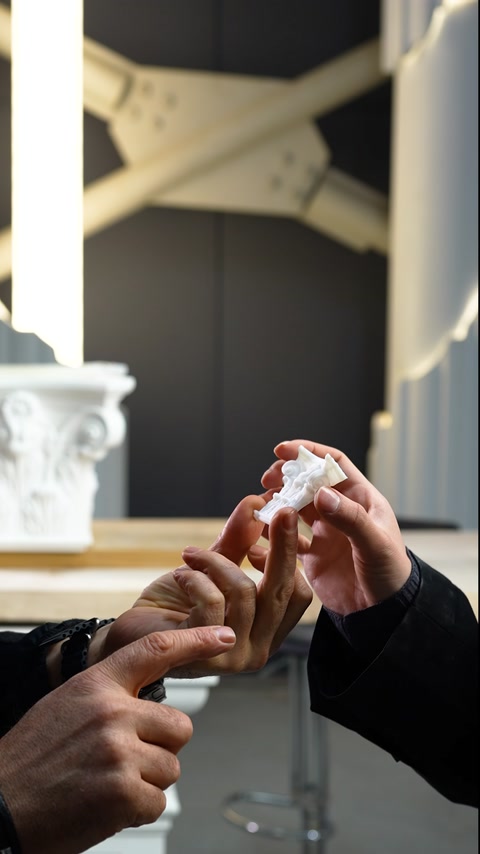 Un piccolo elemento decorativo per colonna viene esaminato da due persone