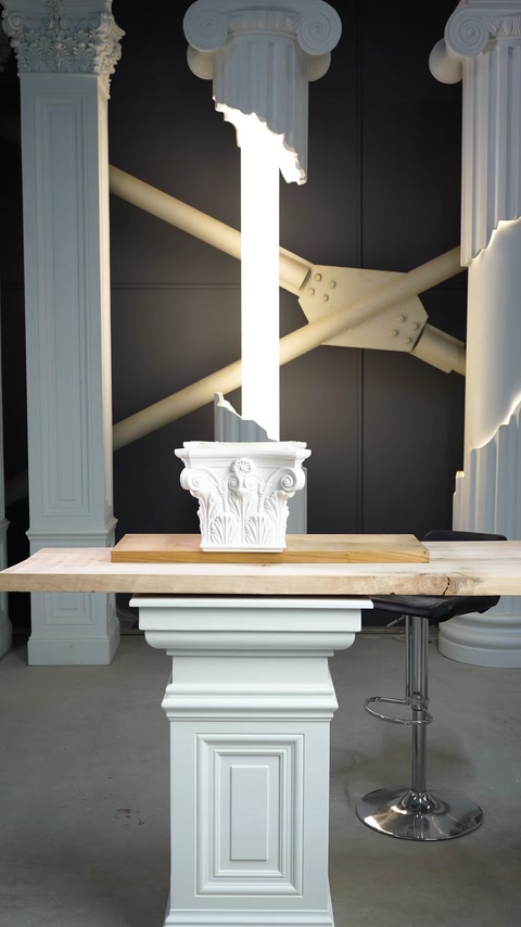 Un capitello bianco con motivi decorativi è esposto su un basamento