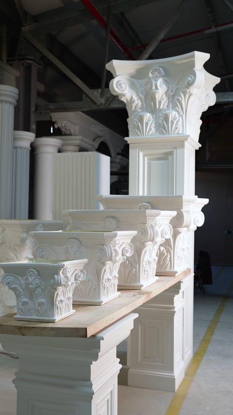 Column capitals in different sizes and patterns are displayed in the workshop