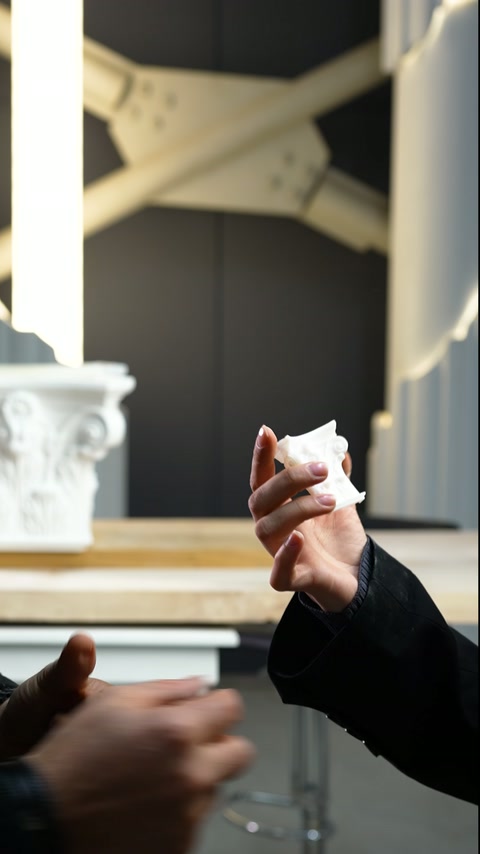 Un piccolo elemento decorativo curvo viene mostrato tra le mani di due persone