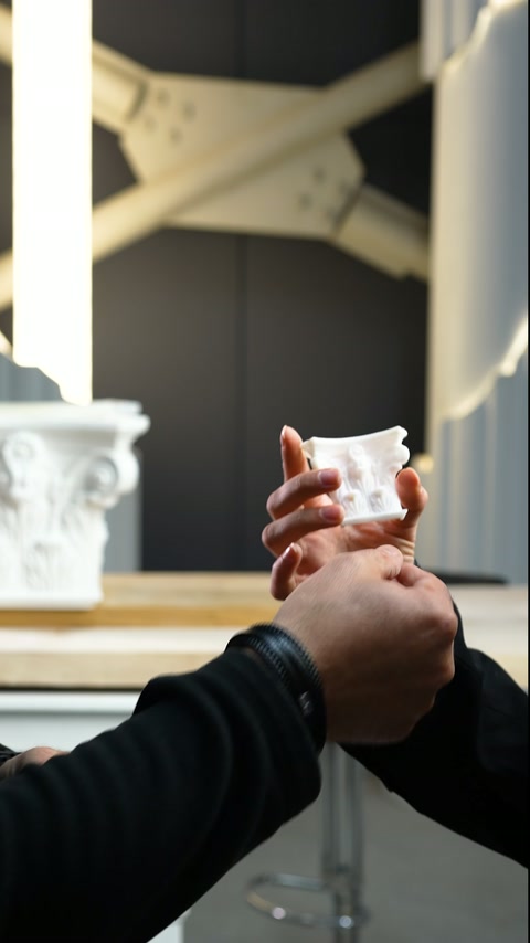 Un pezzo in miniatura decorato viene esaminato da vicino tra due mani