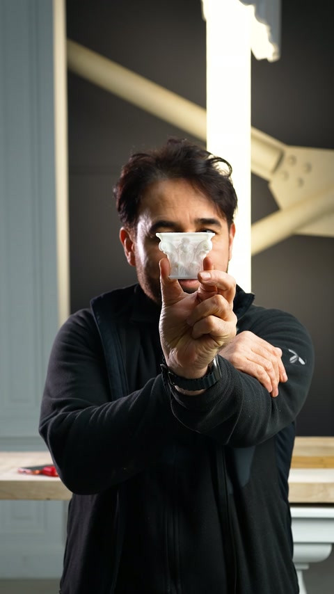 Un piccolo elemento di capitello in miniatura bianco viene presentato con una sola mano