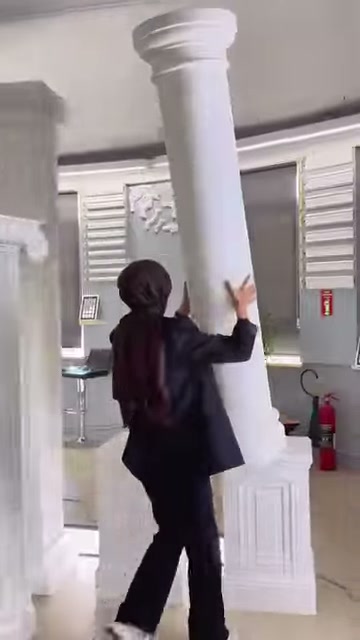 Il presentatore mostra con la mano la superficie liscia del fusto rotondo della colonna bianca.