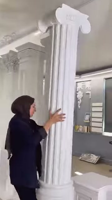 Il presentatore esamina l'arrangiamento dei canali sotto il capitello della colonna sottilmente scanalata.