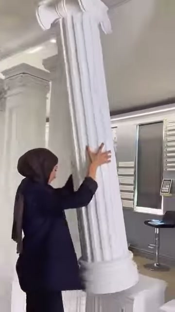 Una colonna scanalata con base rotonda viene mostrata insieme al suo capitello superiore curvilineo.