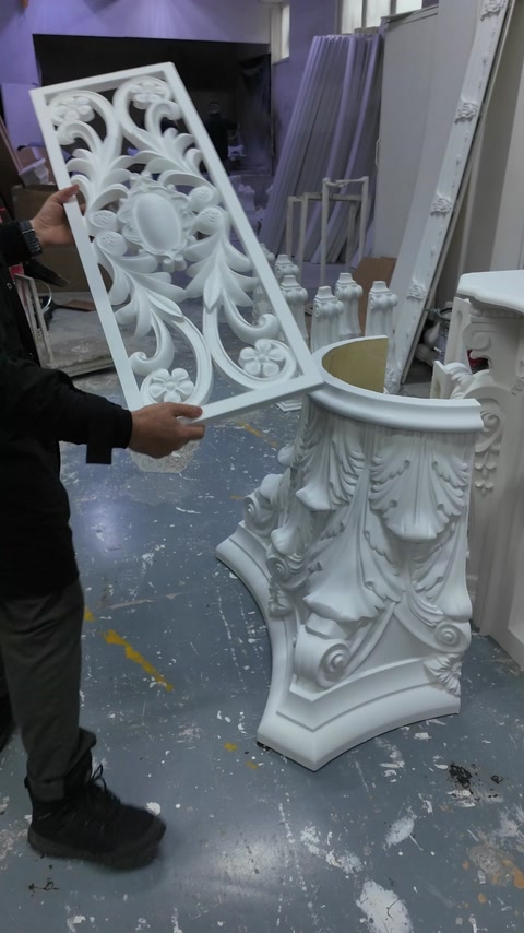 Artigiano che movimenta un grande capitello con ornamento di foglie intagliate