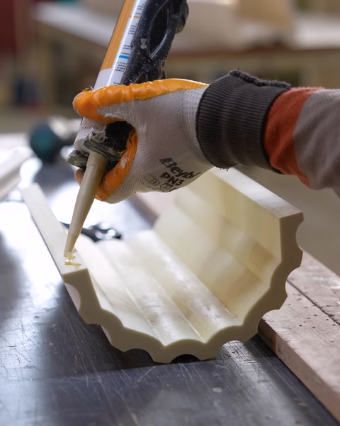Applying adhesive along a curved polyurethane cornice piece