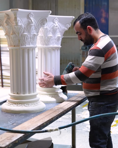 Two finished polyurethane Corinthian-style column capitals standing upright