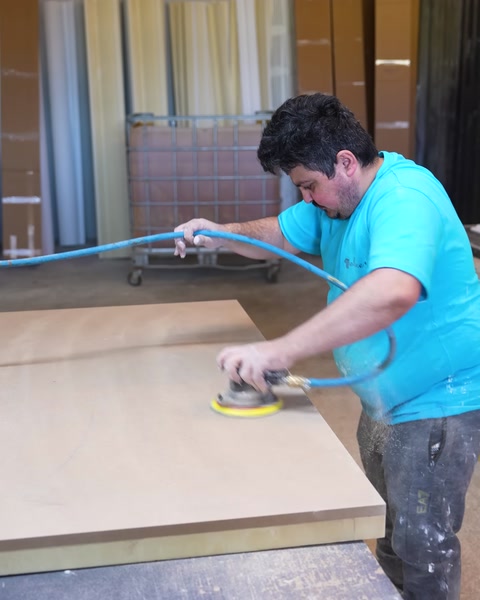 Sanding the edge of the tabletop panel with a power sander