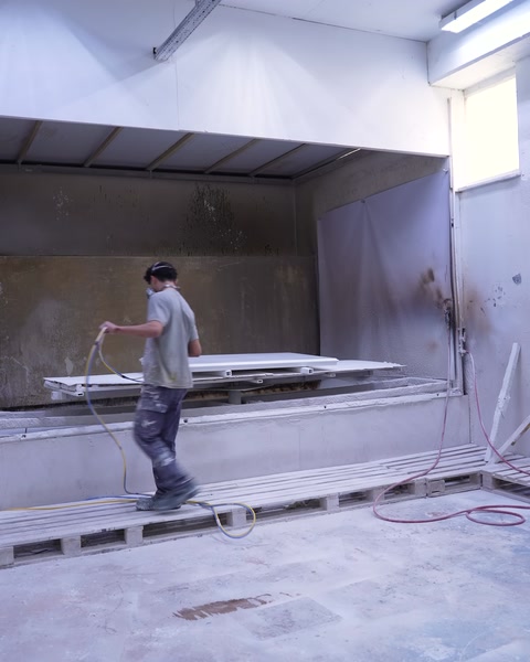 Worker carrying a finished panel into the paint spray booth