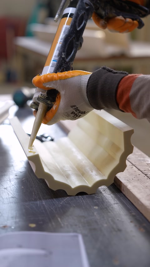 Applicazione di adesivo lungo un pezzo di cornice curva in poliuretano