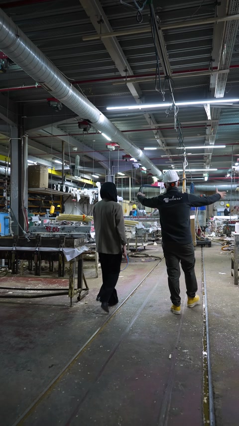 Vengono osservati l'ampia linea di produzione e i banchi di lavoro