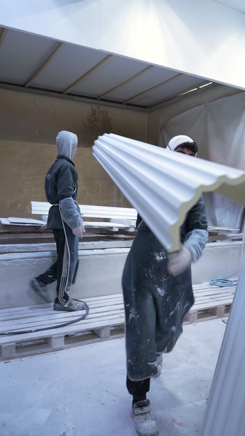 Un ampio profilo per cornice viene trasportato a mano nell'area di produzione