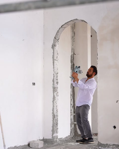 Un operaio installa un arco decorativo su una parete interna