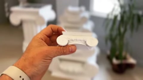 Un piccolo campione di profilo bianco in poliuretano tenuto in mano è mostrato in primo piano