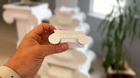 A white curved profile piece is held horizontally in a display area.