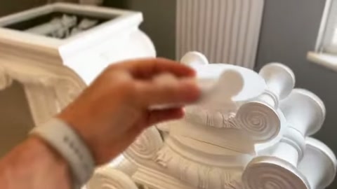 A decorative piece is aligned over the round area of a column capital.