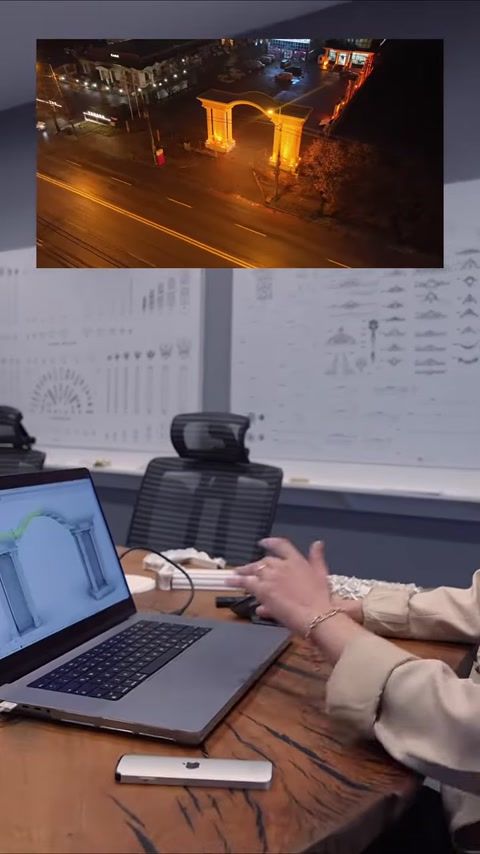 Il modello della colonna sul laptop viene valutato davanti a un pannello con disegni tecnici.