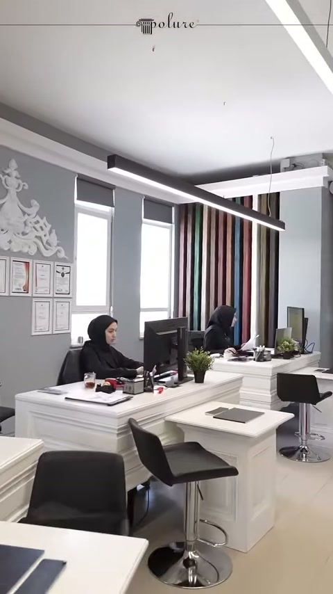 Tavoli di lavoro con computer allineati davanti a pareti grigie decorative
