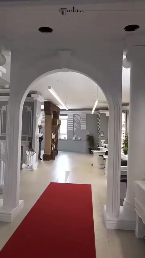 Disposizione ripetuta di colonne ad arco nel corridoio con tappeto rosso