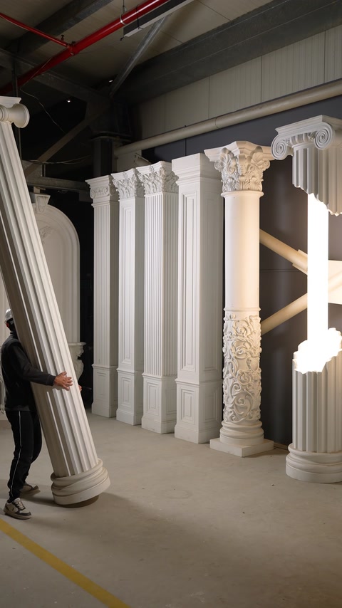 A fluted round column model introduced while being carried by hand in the workshop