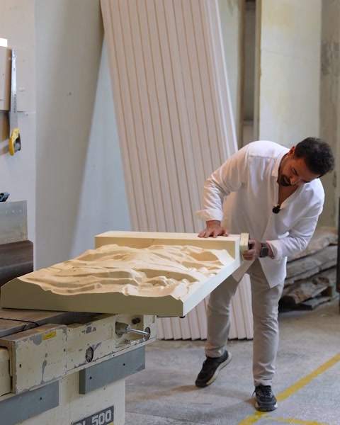 L'operaio leviga e prepara un grande pannello a rilievo per la finitura