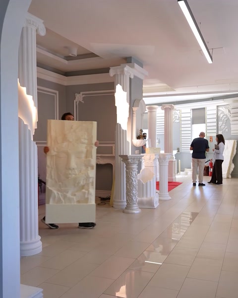 La sala espositiva mostra colonne decorative e un grande pannello di rilievo scultoreo