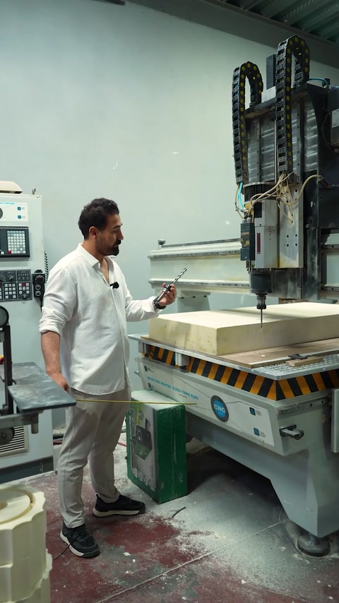 Technician operates machinery beside a large panel manufacturing station