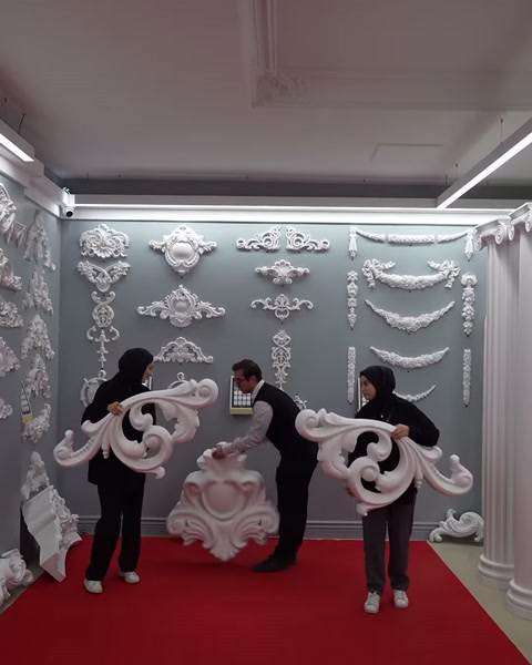 È visibile la forma completa di un ampio modello di cornice trasportato da tre persone.