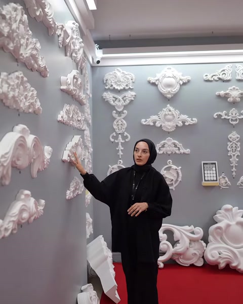 Il presentatore indica le cornici decorative di diverse dimensioni sulla parete.