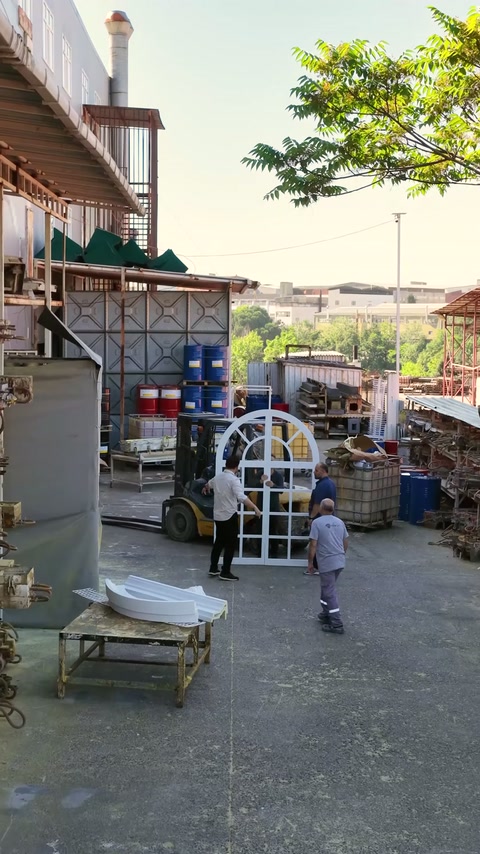 Team lifting large arched window combination in workshop yard