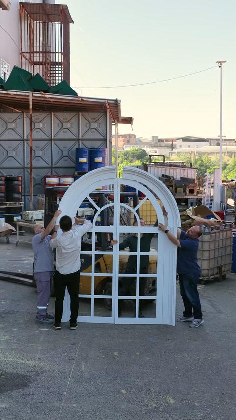 Workers holding curved outer frame of window on both sides