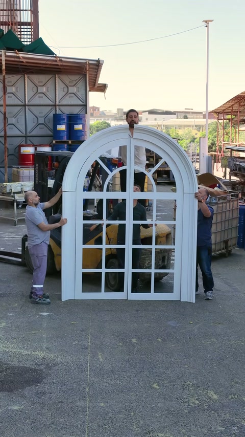 Team displaying completed wide arched window frame standing
