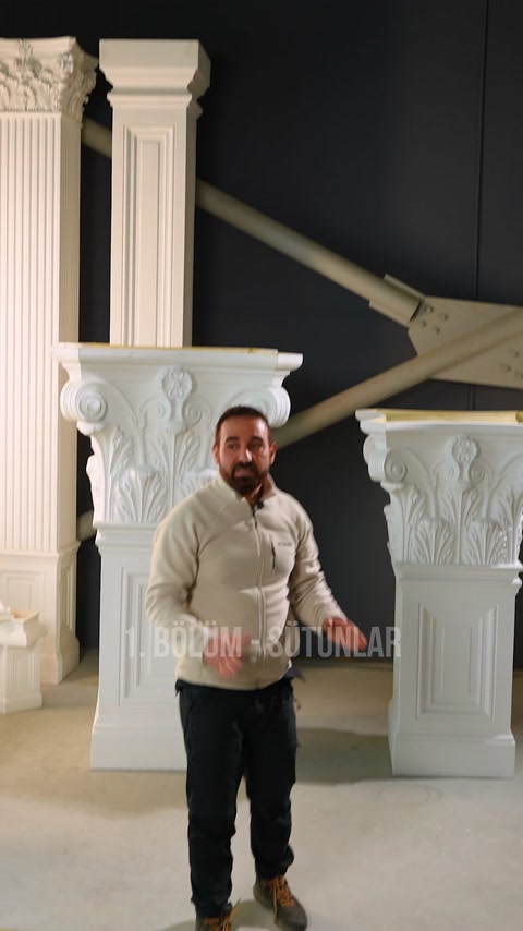 Il presentatore illustra i dettagli tecnici davanti a un grande capitello di colonna ornato.