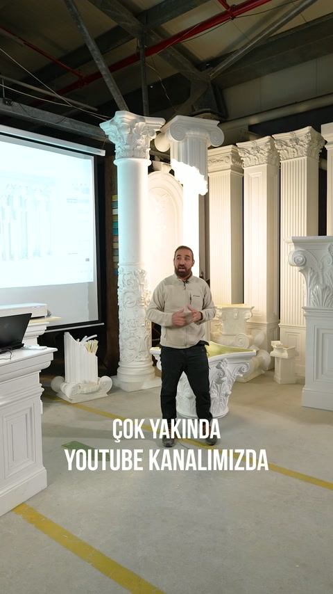 Sunucu, showroom zemininde sıralanan dekoratif sütunları eliyle gösteriyor.