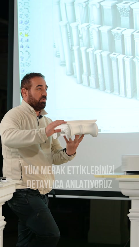 Elde tutulan volütlü başlık parçası, sütun kataloğu önünde tanıtılıyor.