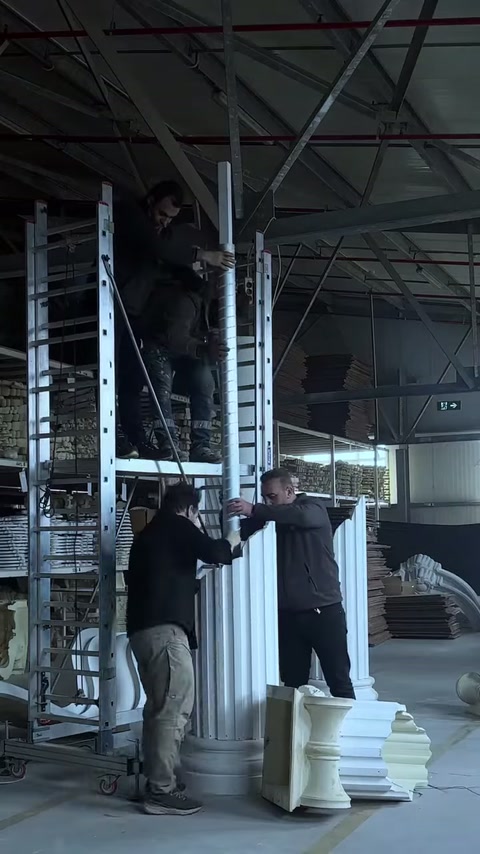 Le sezioni della colonna decorativa scanalata sono mantenute in posizione verticale accanto all’impalcatura.