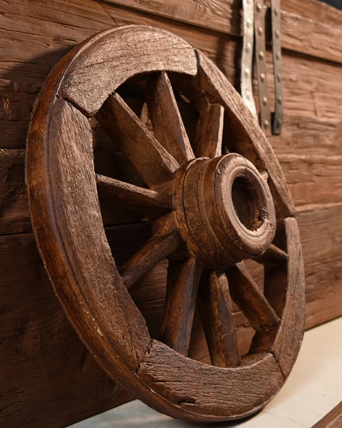 Primo piano di una ruota decorativa da carro con finitura effetto legno invecchiato e cerchiature metalliche