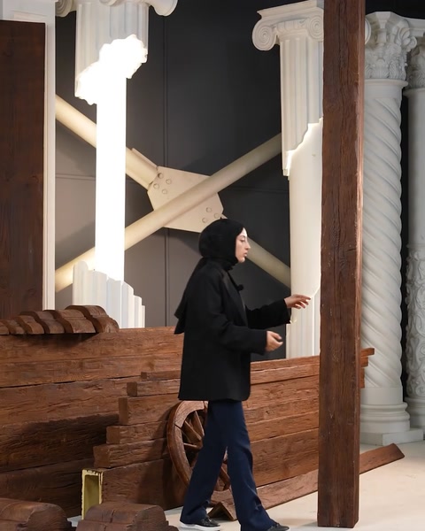La presentatrice cammina verso una colonna di travi in poliuretano impilate in showroom