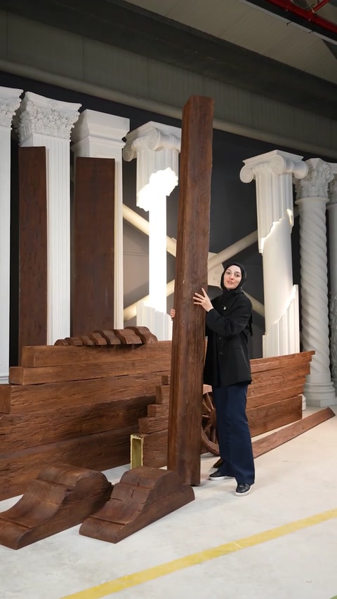 Woman holds vertical polyurethane beam upright against classical columns