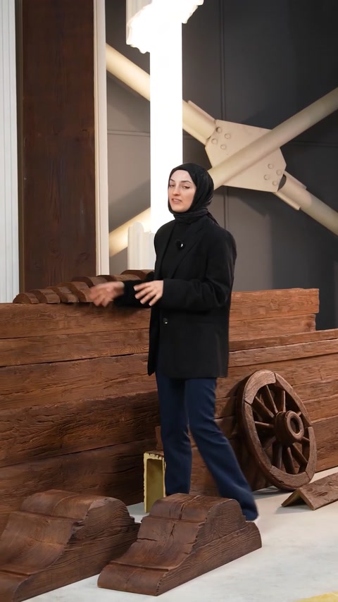 Presenter gestures while standing beside beam and wheel display