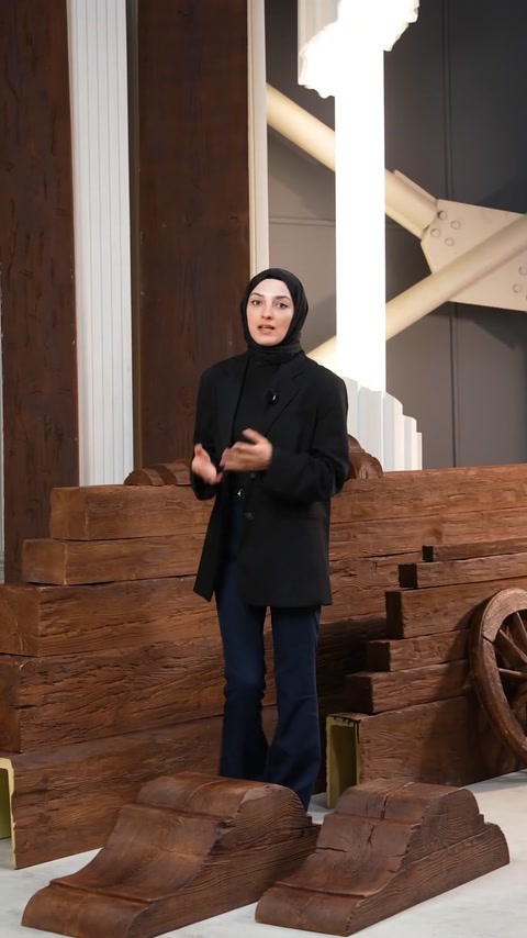 Presenter continues explanation near stacked polyurethane beam wall