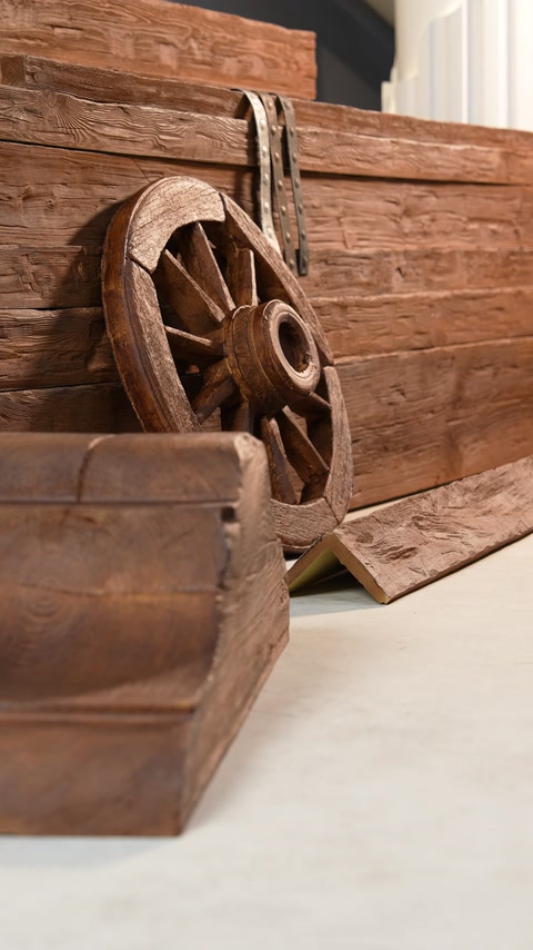Wagon wheel leaning against stacked wood-look polyurethane beams
